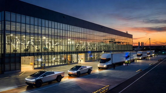 A photorealistic wide-angle view of a gleaming Tesla Gigafactory at dusk, with a line of silver Cybertruck vehicles and white Tesla Semi trucks rolling off the production line onto an illuminated delivery pad, industrial robots visible through massive glass factory walls, warm amber and electric blue lighting, cinematic atmosphere, sense of massive industrial scale and technological precision