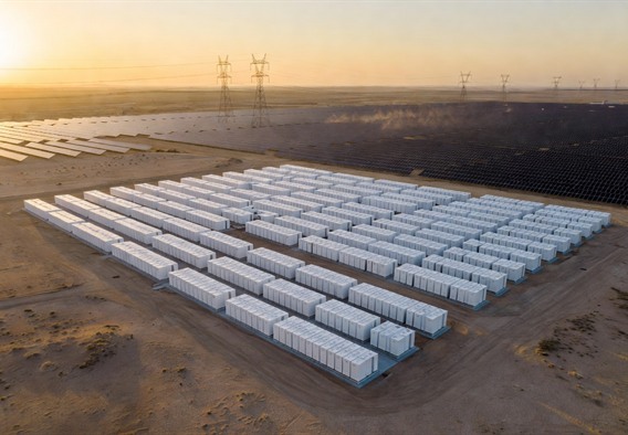 Aerial drone perspective of a vast Tesla Megapack battery installation stretching across a desert landscape, hundreds of white rectangular units arranged in precise grid formation beside a massive solar farm, golden hour light casting long shadows, high-voltage transmission towers marching to the horizon, photorealistic, cinematic quality, 8K detail, muted industrial palette with warm sunset tones